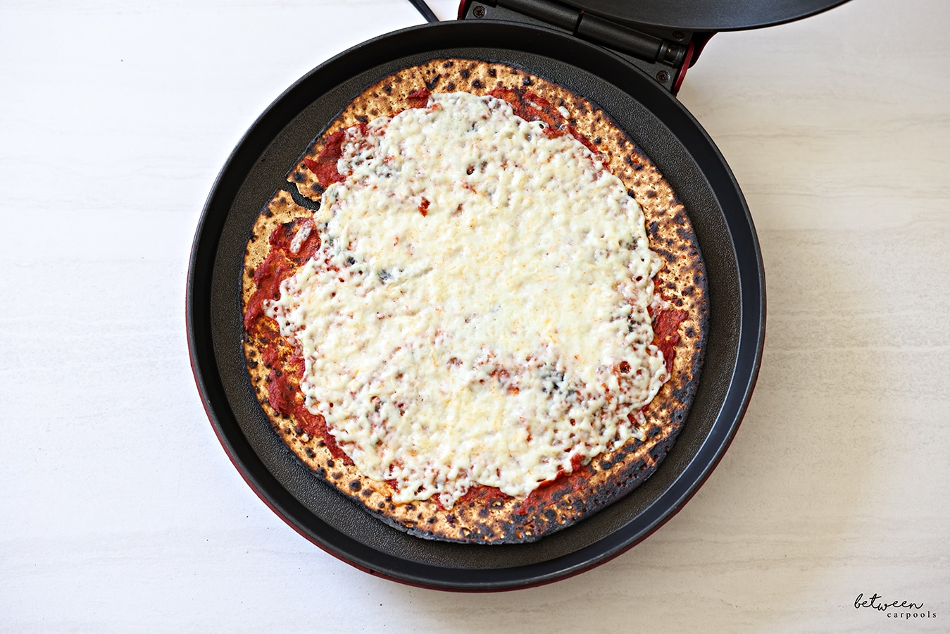 One round Shmurah Matzah with a thin layer of seasoned tomato paste and cheese in a Betty Crocker.